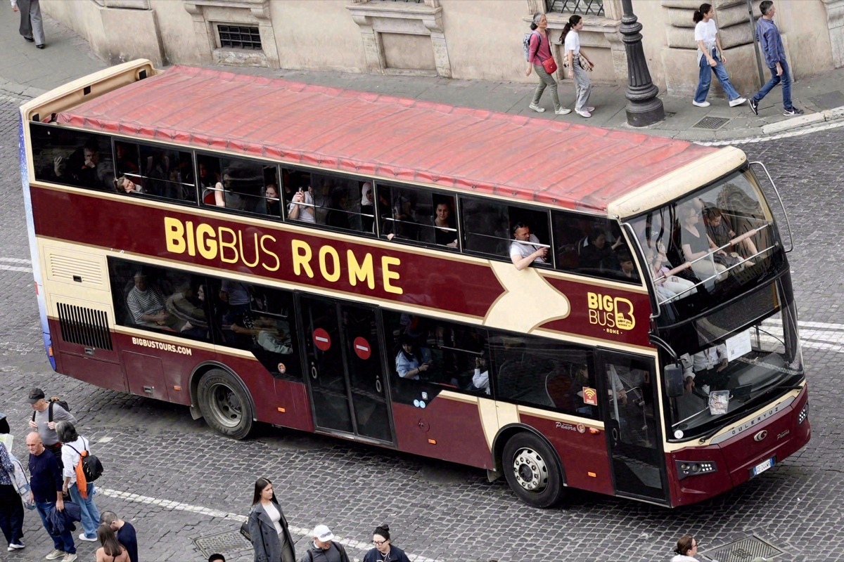 Double-decker bus with tourists on the open top deck in Rome